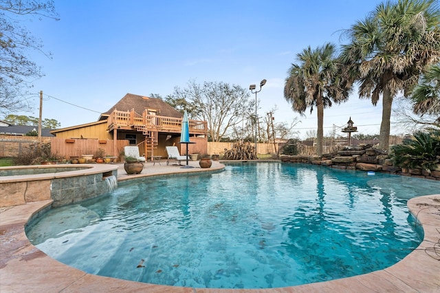 view of swimming pool featuring an in ground hot tub, pool water feature, a wooden deck, and a patio