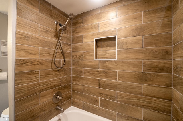 bathroom with tiled shower / bath and toilet