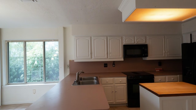 kitchen with black appliances, white cabinetry, sink, wooden counters, and kitchen peninsula