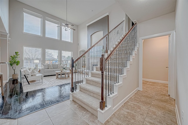 stairway featuring tile patterned floors, ceiling fan, and a high ceiling