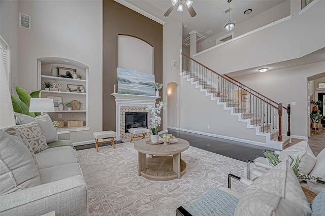 living room with wood-type flooring, built in features, ceiling fan, and a high ceiling