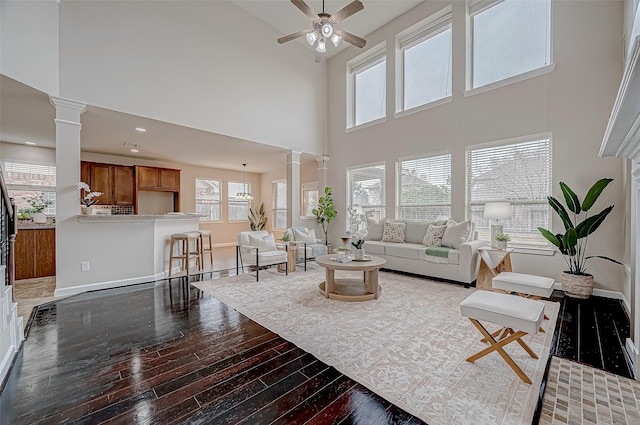 living room with hardwood / wood-style flooring, ceiling fan, and ornate columns