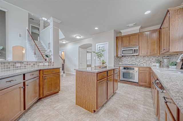 kitchen featuring stainless steel appliances, light stone countertops, sink, and decorative backsplash