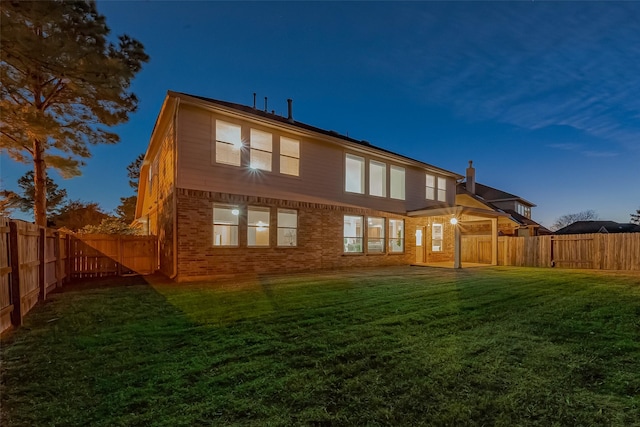 back house at dusk with a lawn