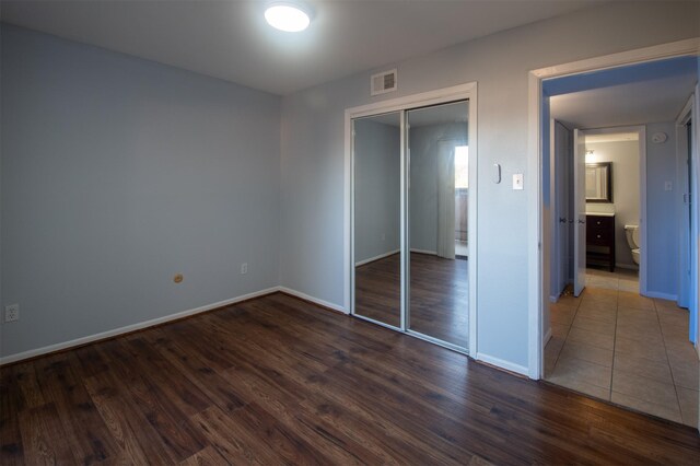 unfurnished bedroom with dark wood-type flooring and a closet