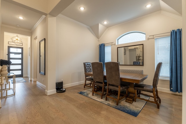 dining room featuring crown molding, vaulted ceiling, a notable chandelier, and light hardwood / wood-style flooring