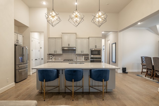 kitchen featuring appliances with stainless steel finishes, pendant lighting, a kitchen bar, and a spacious island