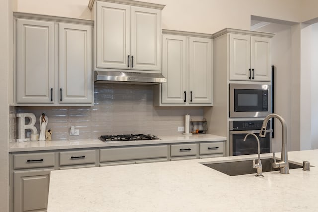 kitchen featuring stainless steel appliances, light stone countertops, sink, and decorative backsplash