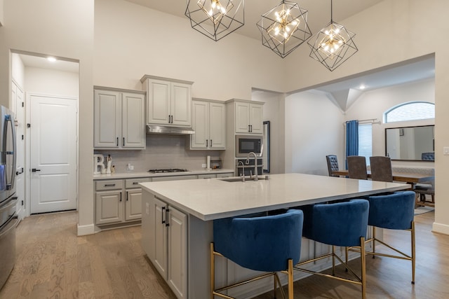 kitchen featuring sink, a breakfast bar area, decorative light fixtures, gas cooktop, and a kitchen island with sink