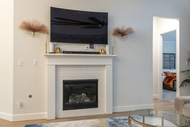 living room featuring a tile fireplace, crown molding, and light hardwood / wood-style floors