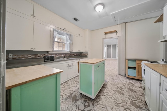 kitchen featuring white cabinetry, wooden counters, sink, and a kitchen island