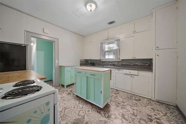 kitchen with white electric range oven, a center island, sink, and white cabinets