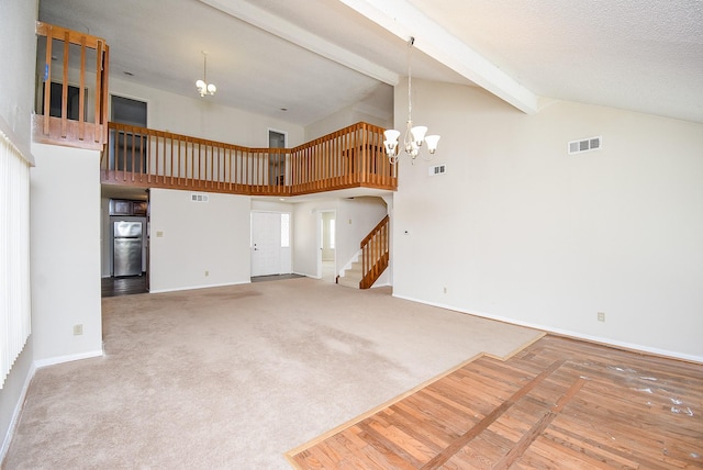 unfurnished living room featuring an inviting chandelier, beam ceiling, high vaulted ceiling, and carpet flooring