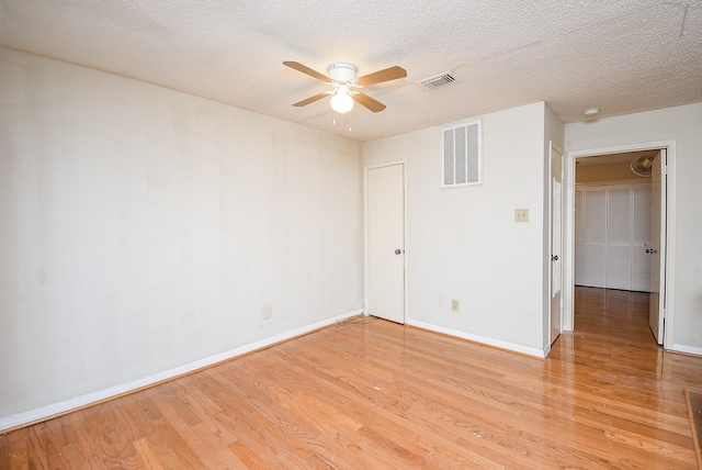 empty room with ceiling fan, light hardwood / wood-style floors, and a textured ceiling