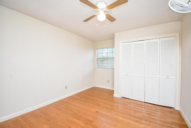 unfurnished bedroom with ceiling fan, a closet, light hardwood / wood-style floors, and a textured ceiling