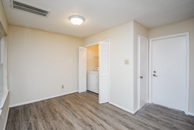 empty room featuring washer / clothes dryer, hardwood / wood-style floors, and a textured ceiling