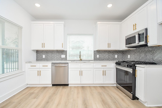 kitchen with sink, light hardwood / wood-style floors, white cabinets, and appliances with stainless steel finishes