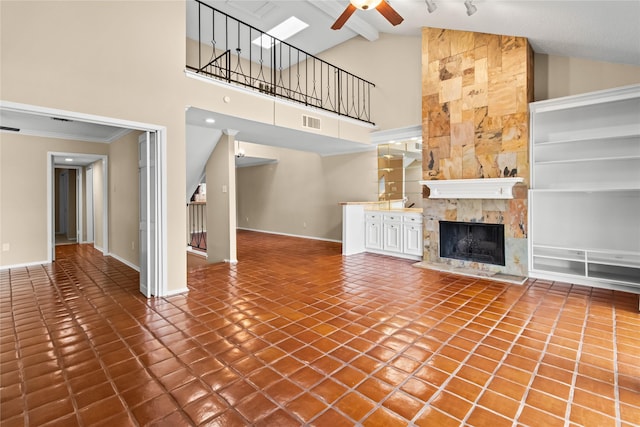 unfurnished living room featuring tile patterned flooring, vaulted ceiling, a tile fireplace, and ceiling fan