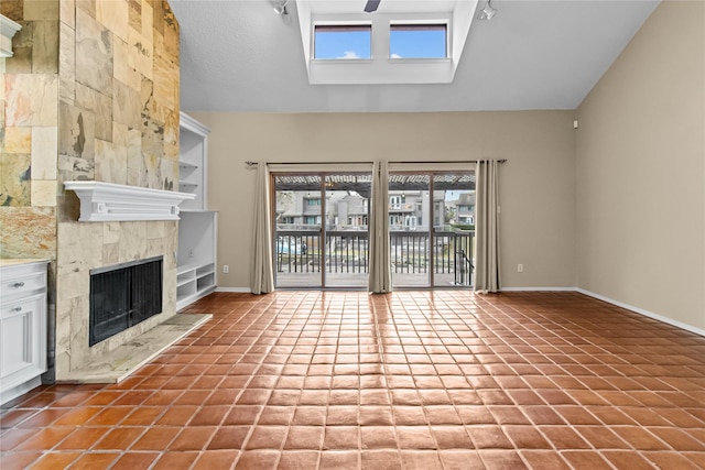 unfurnished living room featuring tile patterned flooring, a premium fireplace, and vaulted ceiling with skylight