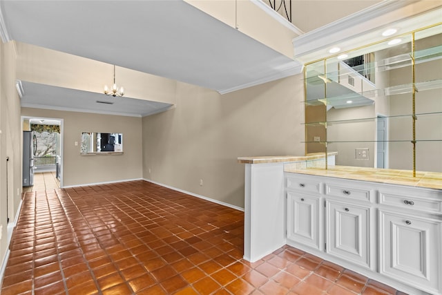 interior space featuring crown molding, stainless steel refrigerator, decorative light fixtures, and white cabinets