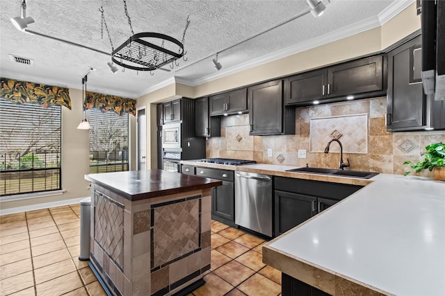 kitchen with appliances with stainless steel finishes, decorative light fixtures, sink, backsplash, and light tile patterned floors