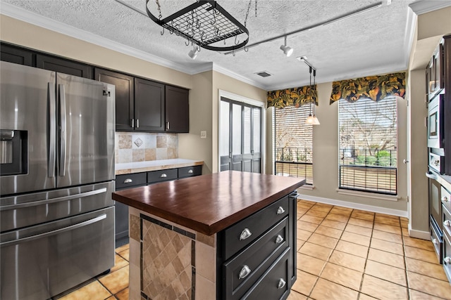 kitchen featuring wood counters, tasteful backsplash, a center island, appliances with stainless steel finishes, and pendant lighting