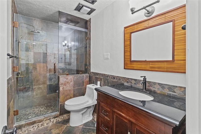 bathroom featuring tile walls, vanity, a textured ceiling, a shower with shower door, and toilet