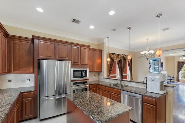 kitchen featuring sink, a center island, hanging light fixtures, dark stone counters, and stainless steel appliances