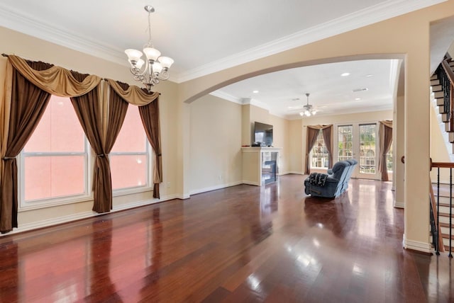 unfurnished living room with dark wood-type flooring, ornamental molding, and ceiling fan with notable chandelier