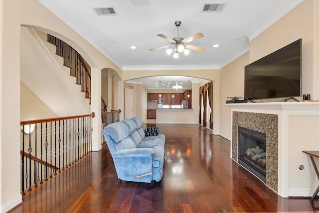 living room featuring a tile fireplace, ornamental molding, ceiling fan with notable chandelier, and dark hardwood / wood-style flooring