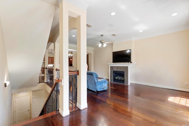 living room featuring ornamental molding, dark wood-type flooring, a tile fireplace, and ceiling fan