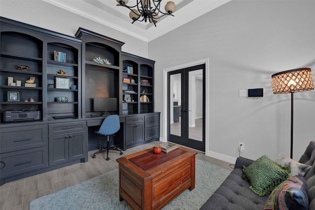 office area with built in desk, an inviting chandelier, crown molding, light wood-type flooring, and french doors