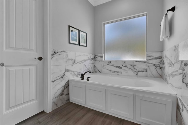 bathroom with tile walls, wood-type flooring, and a tub