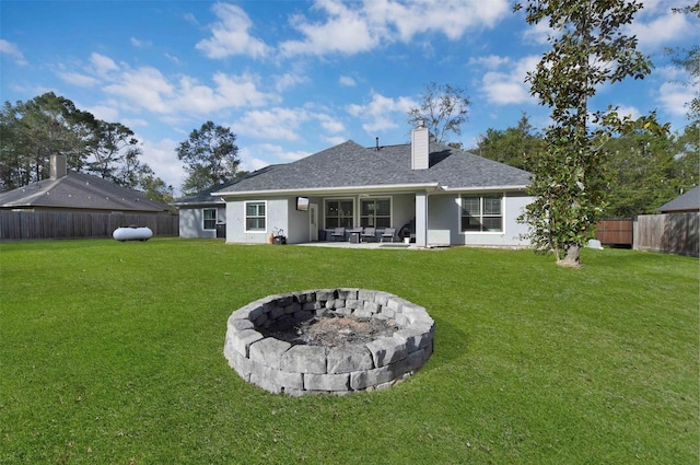 rear view of property with a yard, a patio area, and a fire pit