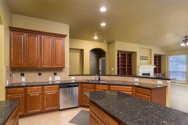 kitchen with sink, dishwasher, ceiling fan, dark stone countertops, and tasteful backsplash