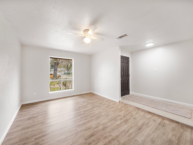 spare room with ceiling fan, a textured ceiling, and light hardwood / wood-style flooring