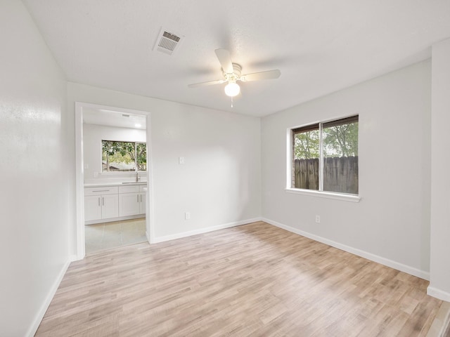 spare room featuring ceiling fan, light hardwood / wood-style flooring, and a healthy amount of sunlight