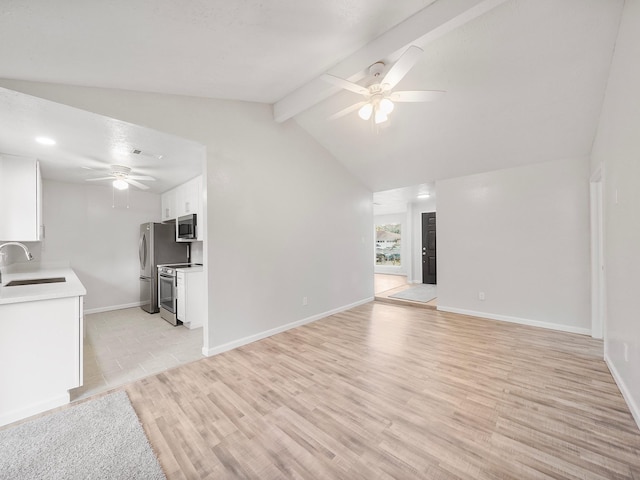 unfurnished living room with sink, vaulted ceiling with beams, ceiling fan, and light wood-type flooring