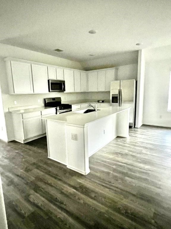 kitchen featuring white cabinetry, stainless steel appliances, dark hardwood / wood-style flooring, and an island with sink