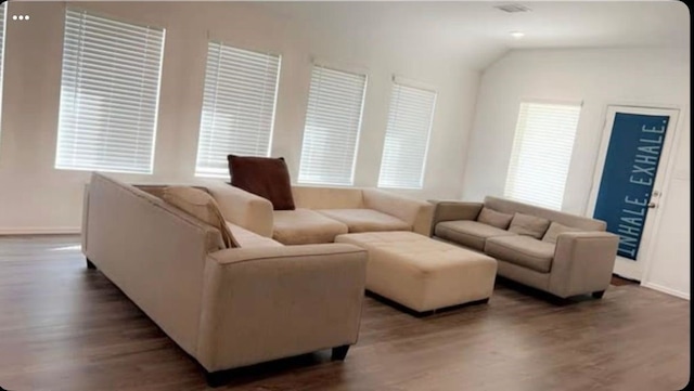 living room featuring dark wood-type flooring, lofted ceiling, and a wealth of natural light