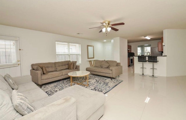 living room featuring light tile patterned flooring, sink, and ceiling fan