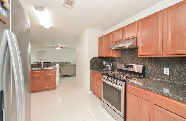 kitchen featuring light tile patterned floors, ceiling fan, appliances with stainless steel finishes, tasteful backsplash, and dark stone counters