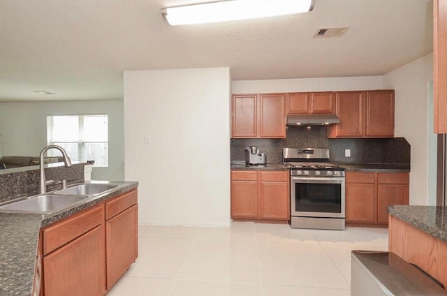 kitchen featuring tasteful backsplash, stainless steel gas range oven, sink, and light tile patterned floors