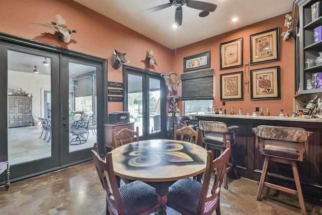 dining space featuring ceiling fan, french doors, concrete floors, and wet bar