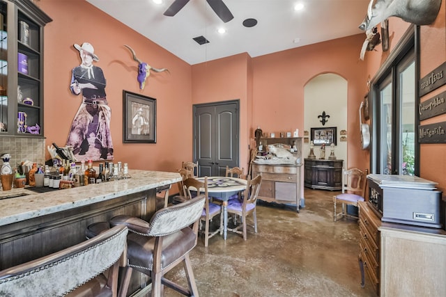 interior space with concrete flooring, ceiling fan, arched walkways, visible vents, and tasteful backsplash