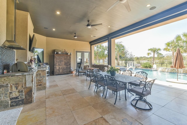 view of patio / terrace featuring outdoor dining area, an outdoor kitchen, a ceiling fan, outdoor wet bar, and an outdoor pool