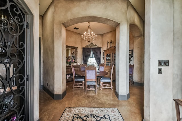 entryway with finished concrete flooring, visible vents, arched walkways, a high ceiling, and a chandelier