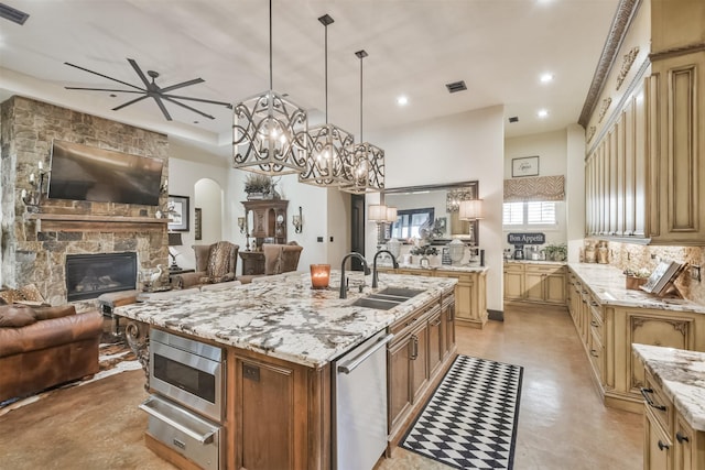 kitchen featuring a spacious island, a sink, open floor plan, a warming drawer, and decorative light fixtures