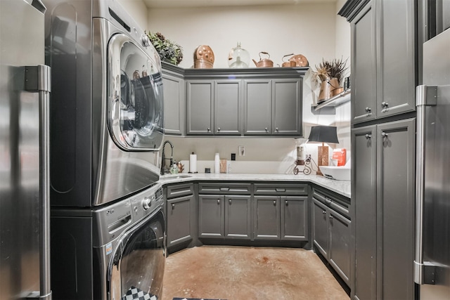 clothes washing area featuring a sink, stacked washer and dryer, and cabinet space