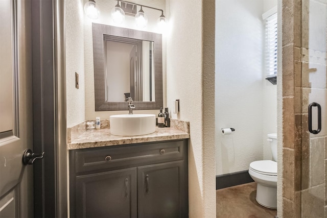 full bath featuring a textured wall, a stall shower, vanity, and toilet